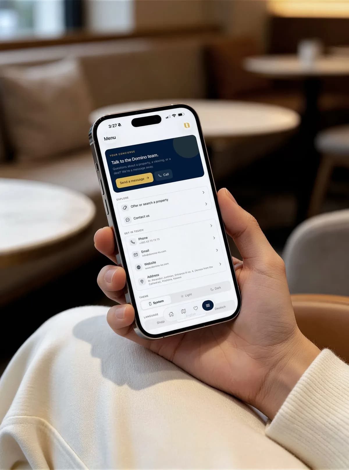 A hand holding a phone with the Domino app menu and Talk to the Domino team