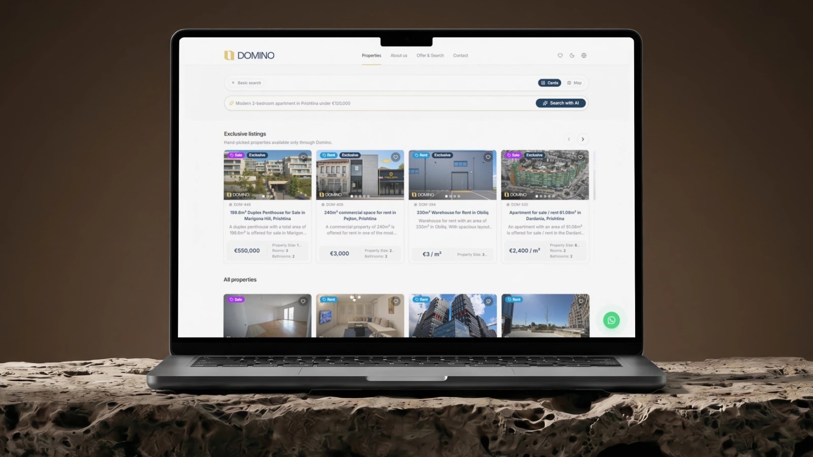 The Domino listings page on a laptop resting on a stone plinth against a warm brown wall