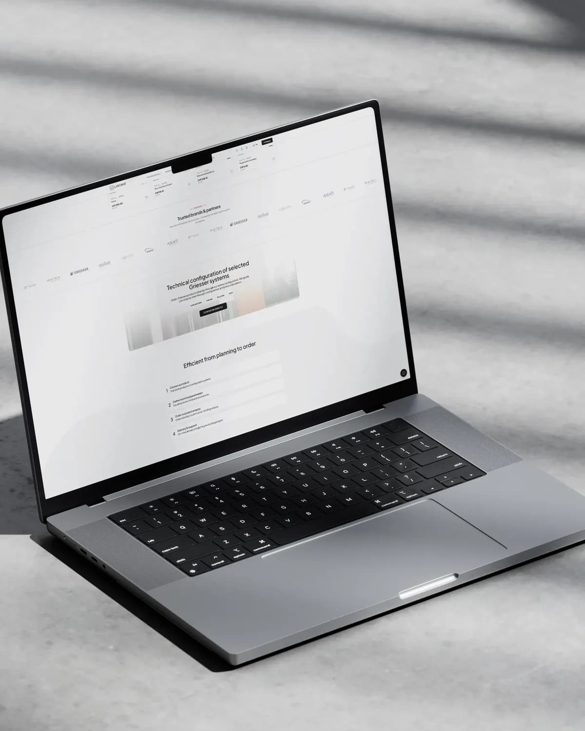 Ein Laptop auf Beton im Licht durch Lamellen, darauf die Seite von Laromat zur technischen Konfiguration von Griesser-Systemen